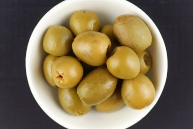 Green pitted olives in a white plate. Olives close-up top view