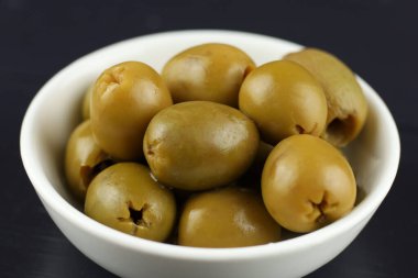Green pitted olives in a white plate. White plate with delicious pitted green olives