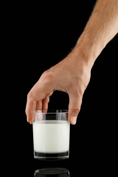 Glass of milk in hand on black isolate