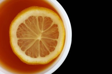 Beyaz bardakta limonlu çay. Siyah arkaplanda çay