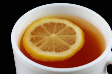 Beyaz bardakta limonlu çay. Siyah arkaplanda çay