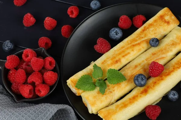 Pancakes rolls with raspberries and blueberries. Traditional breakfast and food.