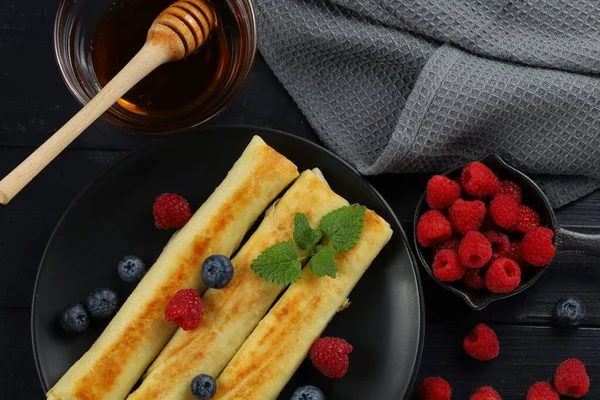 Pancakes rolls with honey and berries.