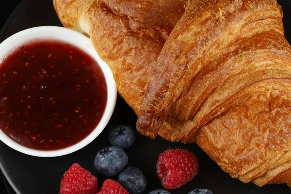 Croissant with jam and berries. Delicious and traditional breakfast.
