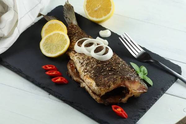 Fried carp fish with vegetables, tomatoes and lemon. Delicious fried fish