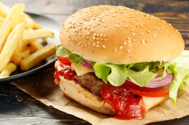 Pirzola, domates, peynir ve sebzeli hamburger. Siyah arka planda izole edilmiş taze lezzetli burger.