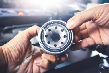 Tamirhanedeki motor yağı sistemi bakımı için tamircinin elindeki yağ filtresi.