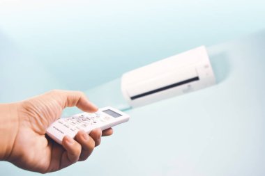 Klima uzaktan kumandası sıcaklığı ayarlamak için insan eliyle basılır.