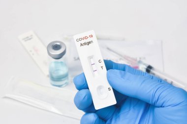 Doktor, hızlı bir antijen test kitinden alınan Covid-19 pozitif sonuç kasetini gösteriyor.