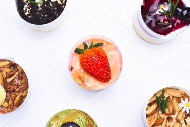 Üstünde taze çilek ve beyaz ahşap masada farklı aromalı cheesecake tatları olan çilekli cheesecake.