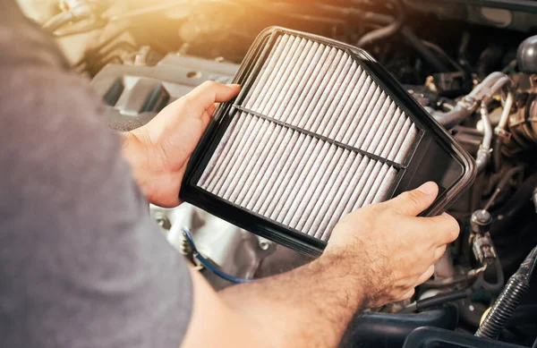 Bir otomobil tamircisi araba motor bakımı için yedek araba hava filtresi taşır