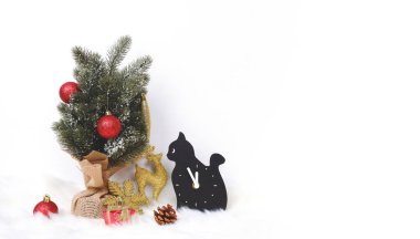 Süslü Noel ağacı, altın geyik ve siyah kedi gözlemi ile süslenmiş mutlu Noeller beyaz arka planda fotokopi alanı olan beyaz kürk halısında.