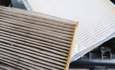 Araba hava filtresi tıkandı ve arka planda plastik bir hava filtresi var.
