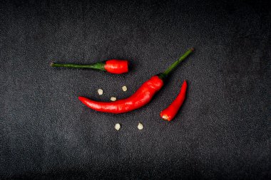Siyah arka planda kırmızı kırmızı kırmızı biber ve yarım kırık kırmızı biber.