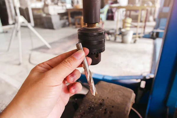 Metal drill bit for drill press machine holding on mechanic hand in the industrial factory.