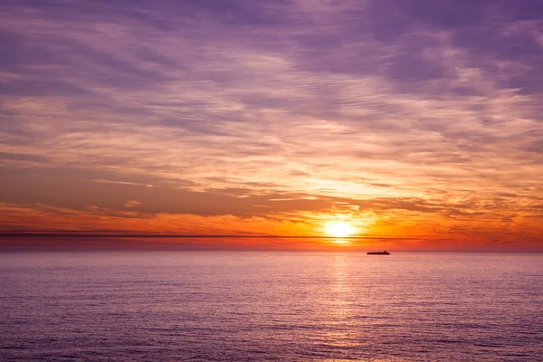Schiff segelt im Ozean bei blauem Sonnenuntergang Stockbild