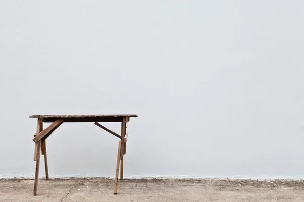 Holztisch gegen weiße Wand — Stockfoto