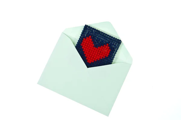 Зеленый конверт с красным вязаным сердцем изолирован на белой спинке — стоковое фото