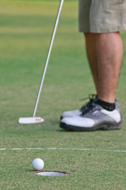 A man putts a golf ball to the hole clipart