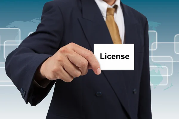 Affärsman Visa ett vitt kort med ordet licens — Stockfoto