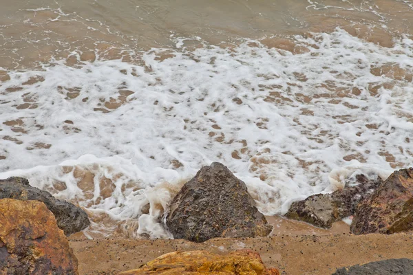 Water swirling around beach rocks — Stock Photo, Image