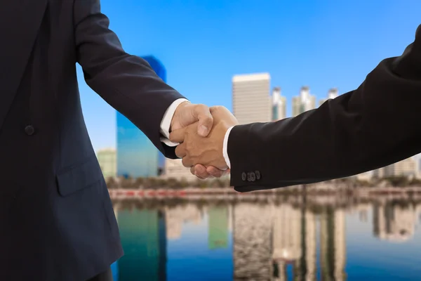 Podnikatel handshake s budováním pozadí — Stock fotografie