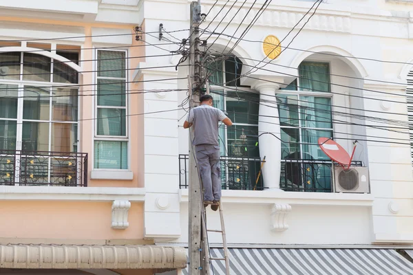 Técnico trabajando con cable delante de la casa —  Fotos de Stock