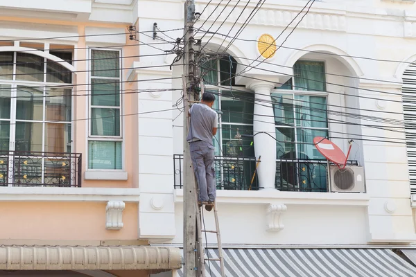 Técnico trabajando con cable delante de la casa —  Fotos de Stock