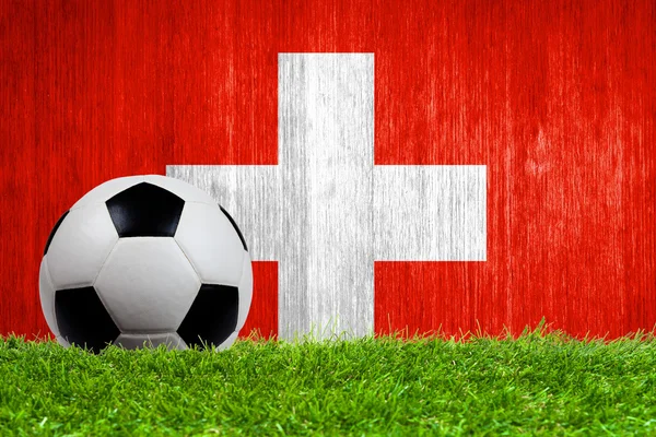 Fotboll på gräs med Schweiz flagga bakgrund — Stockfoto