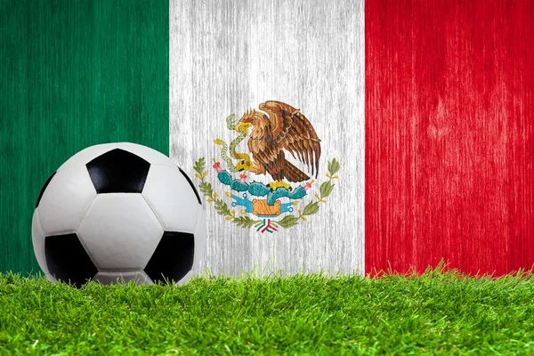 Balón de fútbol sobre hierba con fondo de bandera de México — Foto de Stock