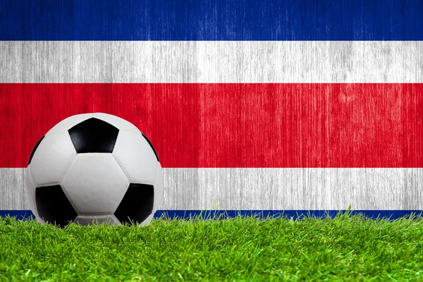 Balón de fútbol sobre hierba con fondo de bandera de Costa Rica — Foto de Stock