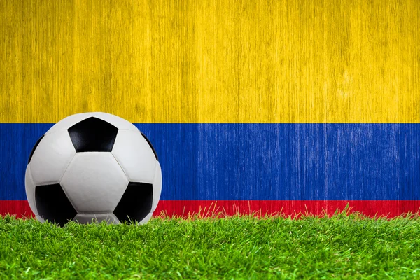 Balón de fútbol sobre hierba con fondo de bandera de Colombia — Foto de Stock