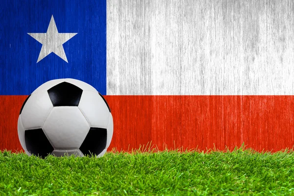 Balón de fútbol sobre hierba con fondo de bandera de Chile — Foto de Stock