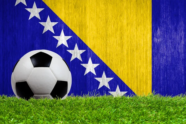 Balón de fútbol sobre hierba con fondo de bandera de Bosnia y Herzegovina — Foto de Stock