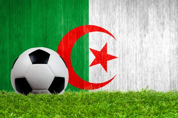 Balón de fútbol sobre hierba con fondo de bandera de Argelia — Foto de Stock