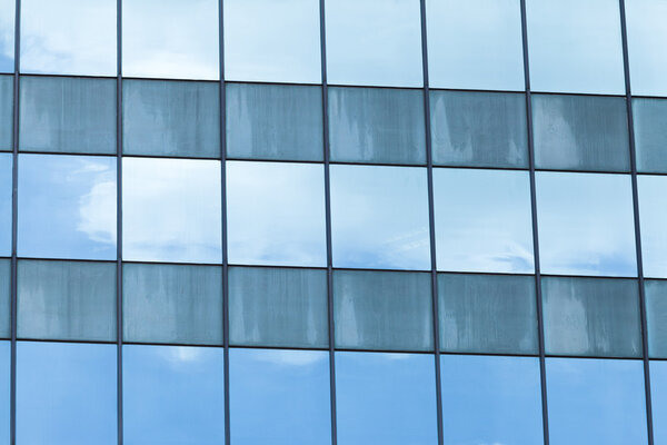 Wide Angle of glass windows on high rise building, mirror cloud on blue sky