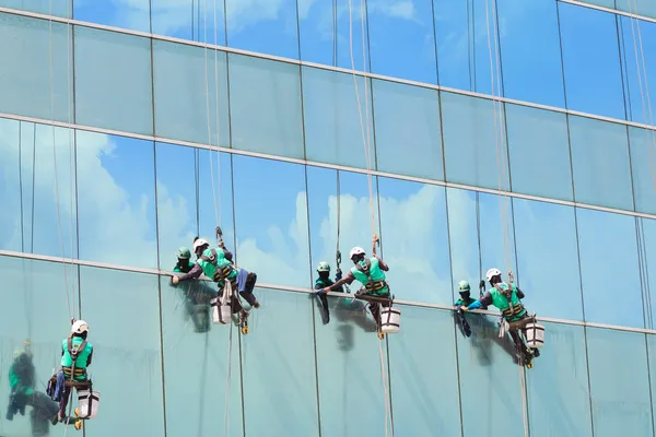 Grupo de trabalhadores serviço de limpeza de janelas em edifício alto — Fotografia de Stock