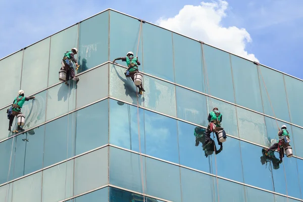 Grupo de trabalhadores serviço de limpeza de janelas em edifício alto — Fotografia de Stock