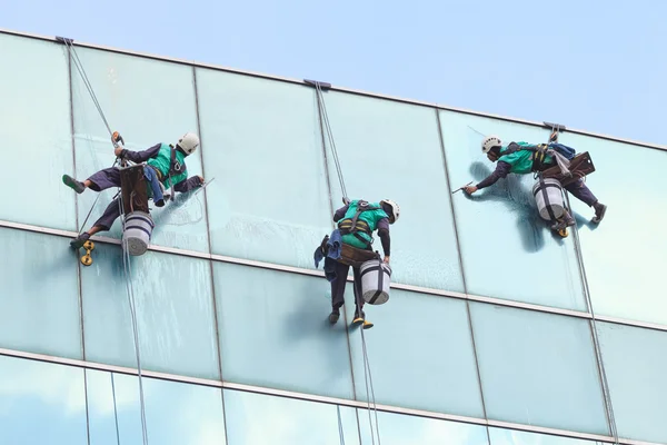 Grupo de trabalhadores serviço de limpeza de janelas em edifício alto — Fotografia de Stock