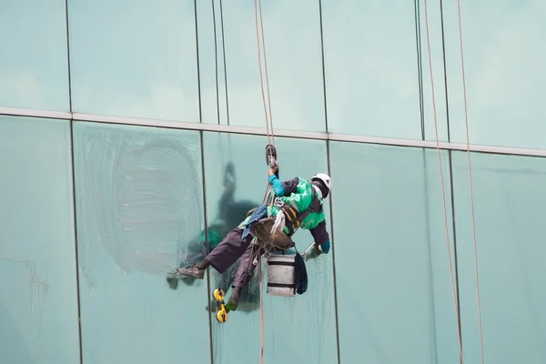 Un ouvrier nettoie les fenêtres sur un immeuble de grande hauteur — Photo