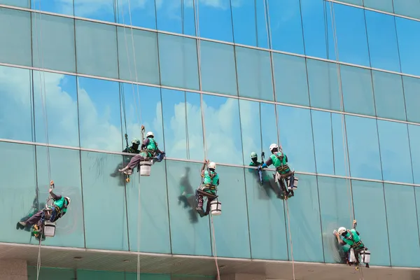 Grupo de trabalhadores serviço de limpeza de janelas em edifício alto — Fotografia de Stock