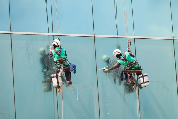 Grupo de trabalhadores serviço de limpeza de janelas em edifício alto — Fotografia de Stock