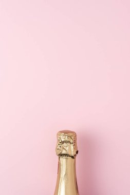 Pembe arka planda altın şampanya şişesi. Asgari parti konsepti.