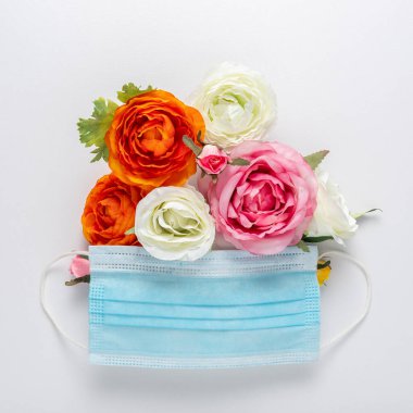 Beyaz arka planda farklı renk çiçekli tıbbi maske. Asgari bahar kavramı.