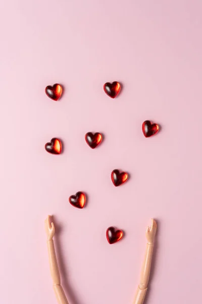Hand of a doll with small hearts on a pink background. Love minimal concept.