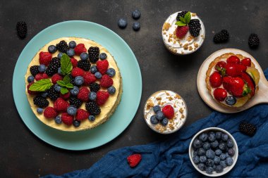 Homemade cake with fresh berries and sweet desserts on dark background. 