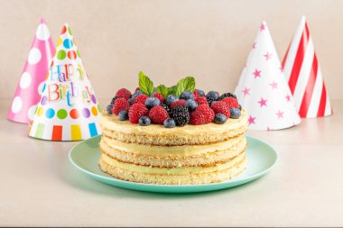 Taze dutlu ev yapımı pasta ve parlak arka planda doğum günü şapkası.. 