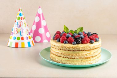 Taze dutlu ev yapımı pasta ve parlak arka planda doğum günü şapkası.. 