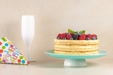 Taze dutlu ev yapımı pasta ve parlak arka planda doğum günü şapkası.. 