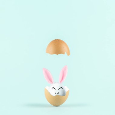 Tavşan kulaklı, yumurta kabuklu beyaz yumurta pastel mavi arka planda. Paskalya asgari konsepti. Yaratıcı Mutlu Paskalyalar veya Bahar Düzenlemesi.